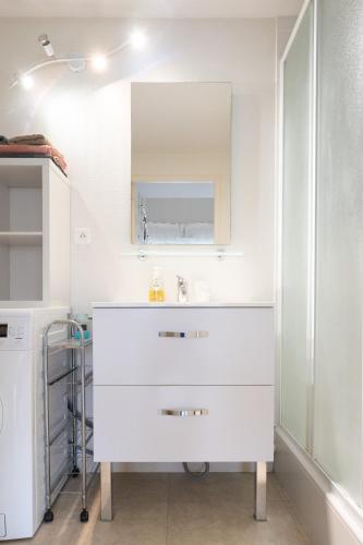 une salle de bain blanche avec un lavabo et un miroir dans l'établissement COSY Home - 2 à 4 pers - Aéroport - vieux Blagnac, à Blagnac