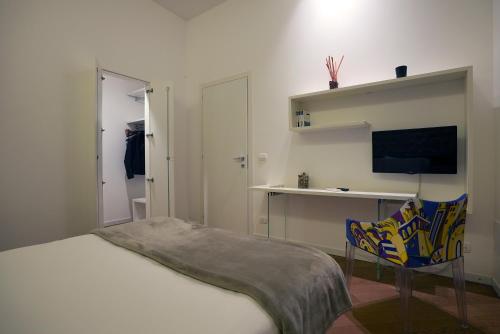 a bedroom with a bed and a tv and a chair at Keys of Sicily - Appartamenti Modica Bassa in Modica