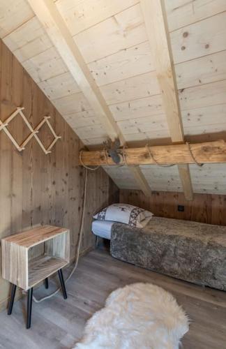 Cette chambre mansardée comprend un lit et une table. dans l'établissement Charmant chalet cosy & paisible en pleine nature - refuge idyllique pour 5p, à Gérardmer