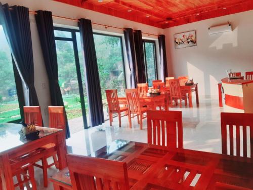 a dining room with wooden tables and chairs and windows at Trang an green river homestay in Ninh Binh