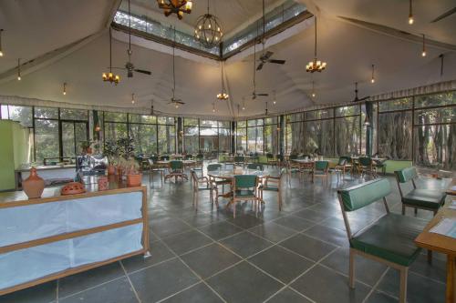un restaurante con mesas, sillas y ventanas en Bison Retreat - Pench, 