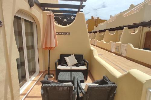 a balcony with chairs and an umbrella on a building at Casa Donn - El Sultán 63 - luxury 3 bed Villa with fast fibre internet in Corralejo