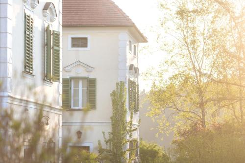 a white building with green shutters on it at Schlossgut Gundersdorf in Klagenfurt