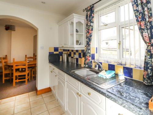 uma cozinha com um lavatório, uma janela e uma mesa em Eusebank em Pooley Bridge