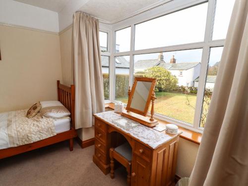 1 dormitorio con escritorio, espejo y ventana en Eusebank en Pooley Bridge