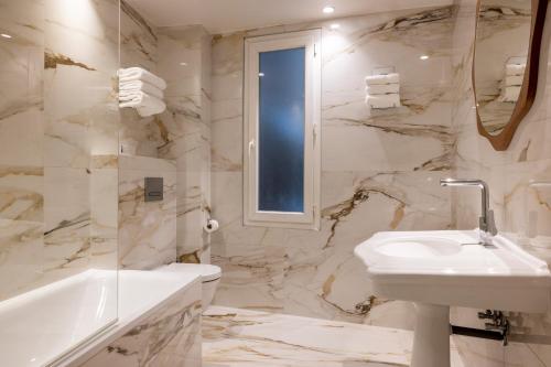 a bathroom with a sink and a toilet and a tub at Hotel Michelet Odeon in Paris