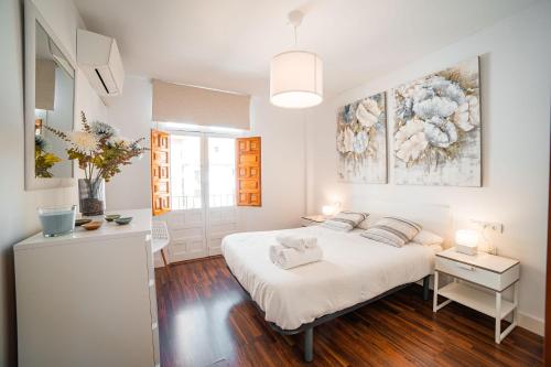 a white bedroom with a bed and a painting on the wall at Apartamento La Tana centro in Granada