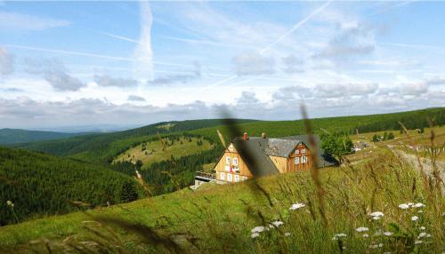 Bouda Klínovka في سبيندلروف ملين: منزل على جانب تل مع التلال الخضراء