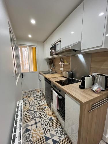 une cuisine avec des armoires blanches et un comptoir dans l'établissement Riva, Appt rénové dans le bourg de Ouistreham, à Ouistreham