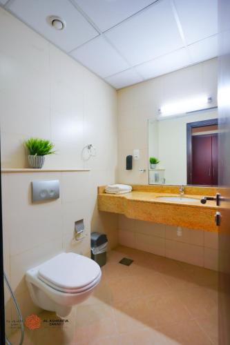 a bathroom with a toilet and a sink and a mirror at Alashrafia Saray, Lovely 2 BR apartment in Sport city in Dubai