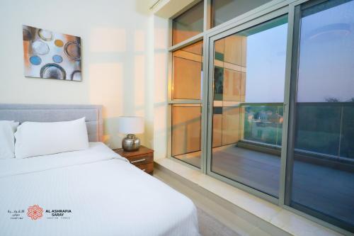 a bedroom with a bed and a large window at Alashrafia Saray, Lovely 2 BR apartment in Sport city in Dubai