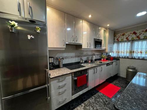 Precioso apartamento renovado en Avilés في أفيليس: مطبخ مع دواليب بيضاء وثلاجة ستانلس ستيل
