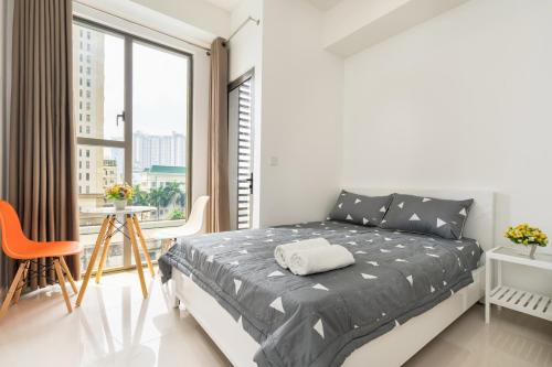 een witte slaapkamer met een bed en een groot raam bij Stylish Studio The Tresor in Ho Chi Minh-stad