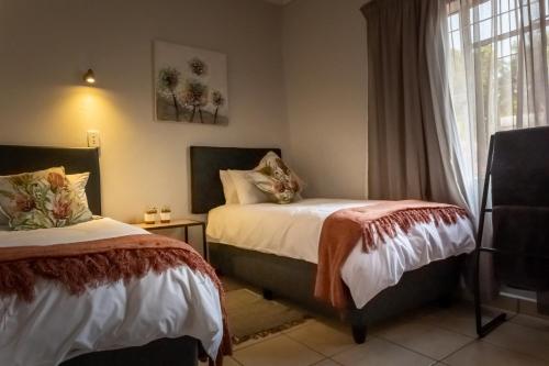 Pretoria的住宿－VillaZek a modern 2 bedroom open- plan apartment with parking，一间卧室设有两张床和窗户。