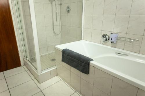 baño con ducha y lavamanos con toalla azul en VillaZek a modern 2 bedroom open- plan apartment with parking, en Pretoria