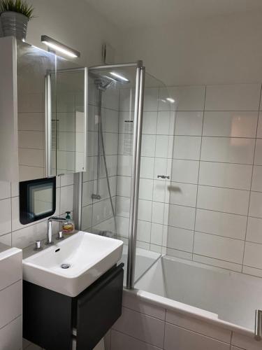 a bathroom with a sink and a shower and a tub at Längengrad 67 in Fehmarn