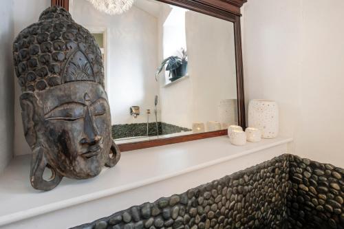 a mirror with a statue of a head on a wall at The Colour House, Kendal Getaway in Kendal