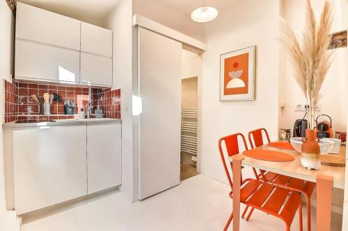 une cuisine avec des armoires blanches et une table et des chaises dans l'établissement Studio Orange - Plein Centre, à Nîmes