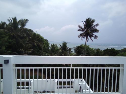 a balcony with a view of the ocean and palm trees at The Moose Weligama in Weligama