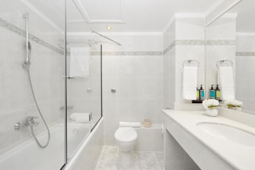 a white bathroom with a shower and a toilet at Grand Hotel Palace in Thessaloniki