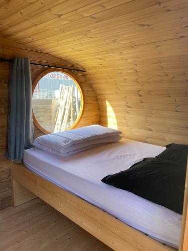 a bed in a wooden room with a round window at Camping de la Bageasse in Brioude