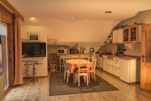 een keuken met een tafel met stoelen en een televisie bij Ferienwohnung Sigrid & Ferdinand BERGINC in Hollenstein an der Ybbs