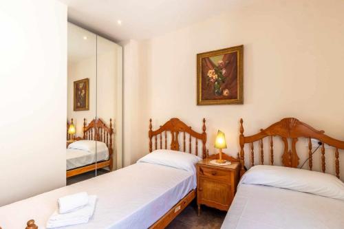 een slaapkamer met 2 bedden en een spiegel bij Port de Llançà 34 Apartamento con vistas playa in Girona