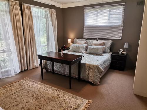 1 dormitorio con 1 cama, mesa y ventanas en Green Hills Farm House, en Drummond