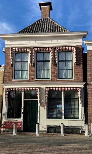 a brick house with a green door on a street at Boutique Hotel De Eilanden in Harlingen