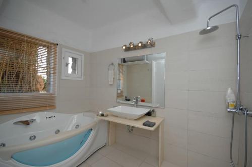 a bathroom with a tub and a sink and a shower at Nefeli Sea View Holiday House in Mýkonos City