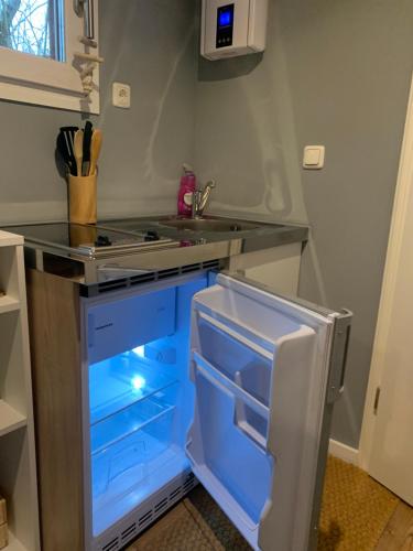 a kitchen with an open refrigerator with blue drawers at Tiny-Ferienwohnungen Hellerau in Dresden