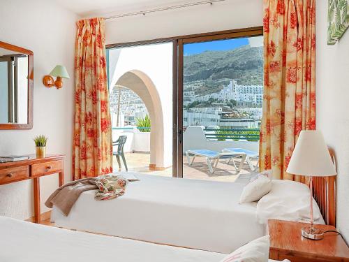 a bedroom with a bed and a large window at Apartamentos Laguna in Puerto Rico de Gran Canaria