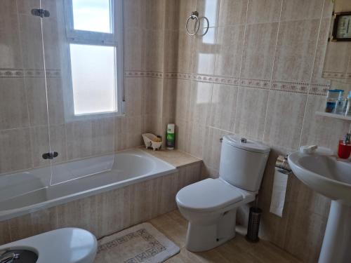 a bathroom with a toilet and a tub and a sink at Pareado Mediterrania in Benicarló