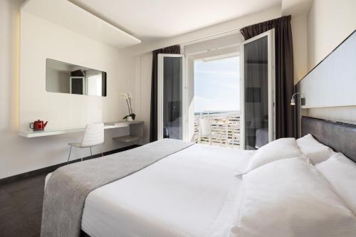 a bedroom with a large white bed and a window at Baldinini Hotel in Rimini