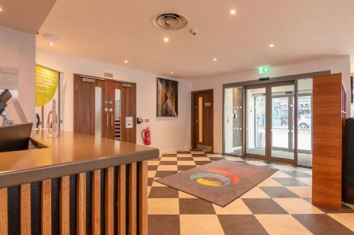 a lobby with a counter and a checkered floor at Ramada Encore Leicester City Centre in Leicester