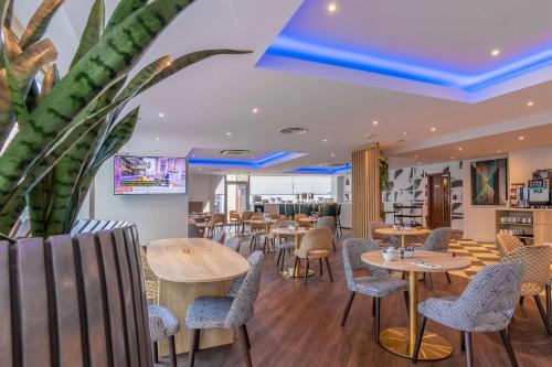 a restaurant with tables and chairs and a plant at Ramada Encore Leicester City Centre in Leicester