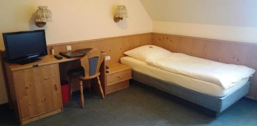 a small bedroom with a bed and a desk with a computer at Gasthof zur Schwane in Abtswind