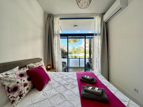 a bedroom with a bed with pink pillows and a window at Vilamoura Prestige With Pool by Homing in Vilamoura