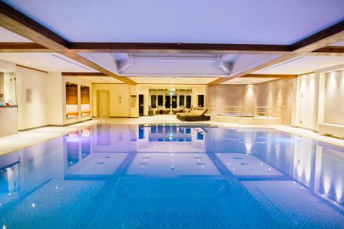 an indoor swimming pool in a house with a large pool at Kettering Park Hotel and Spa in Kettering