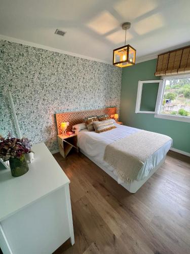 1 dormitorio con cama y pared con papel pintado con motivos florales en La casita de Ouriceira, en Combarro