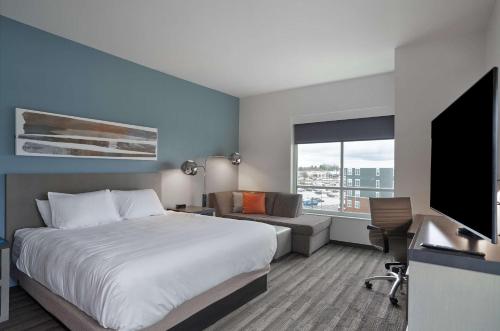 a hotel room with a bed and a flat screen tv at Hyatt House Louisville East in Louisville
