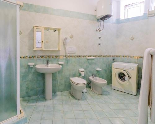 a bathroom with a sink and a toilet and a washing machine at Lucia Maison in Ischia
