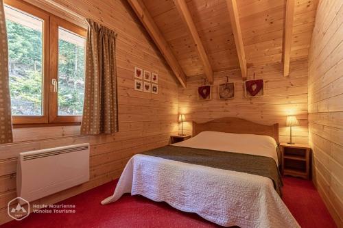 a bedroom with a bed in a wooden cabin at Chalet Deleglise 1 in Valfréjus