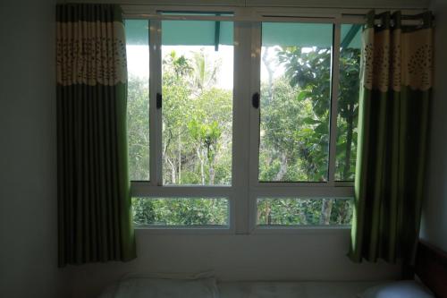 a window in a bedroom with a view of trees at SpiceBuds FarmStay - Ramakkalmedu in Idukki