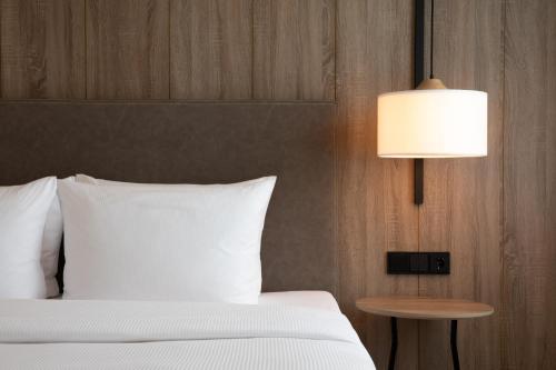ein Schlafzimmer mit einem weißen Bett und einer Lampe in der Unterkunft AC Hotel by Marriott Berlin Humboldthain Park in Berlin