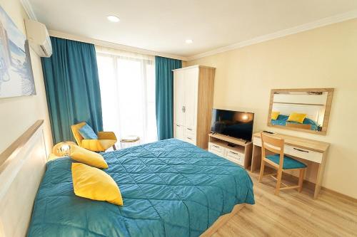a bedroom with a bed and a desk and a television at Burgas Beach Resort Apartments in Burgas City