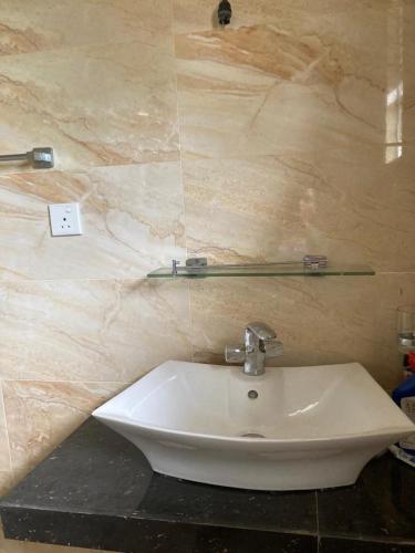Baño con lavabo blanco y pared de mármol en Kenz Villa en Colombo