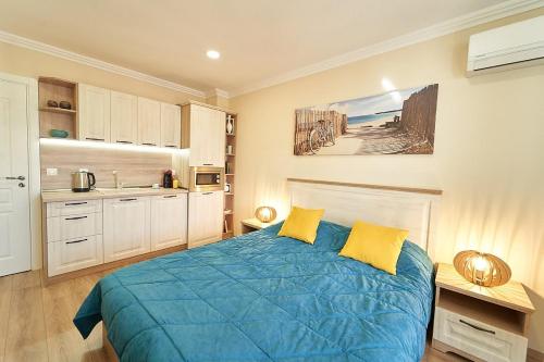 een slaapkamer met een blauw bed met gele kussens bij Burgas Beach Resort Apartments in Boergas