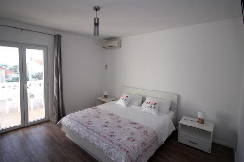 a white bedroom with a bed and a large window at Apartment Orebic 4526b in Orebić