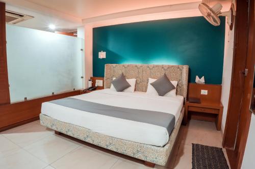 a bedroom with a large bed with a blue wall at Pleasure Inn in Bhopal